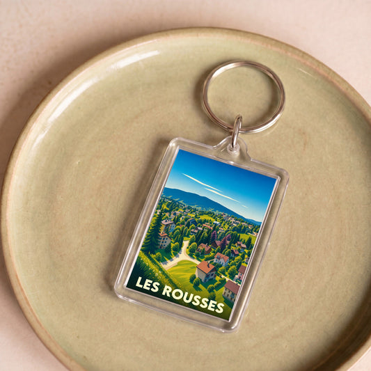 Porte-clés souvenir de la ville de Les Rousses avec une illustration stylisée de son paysage montagneux.