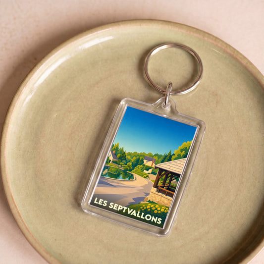 Porte-clés souvenir de la commune de Les Septvallons avec une illustration stylisée d'un paysage de village.