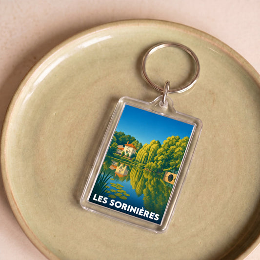 Porte-clés souvenir de la ville de Les Sorinières avec une illustration stylisée d'un paysage naturel.