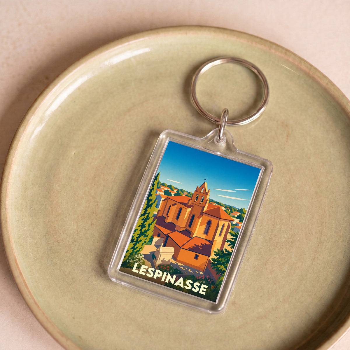 Porte-clés souvenir de la ville de Lespinasse avec une illustration stylisée de son église.