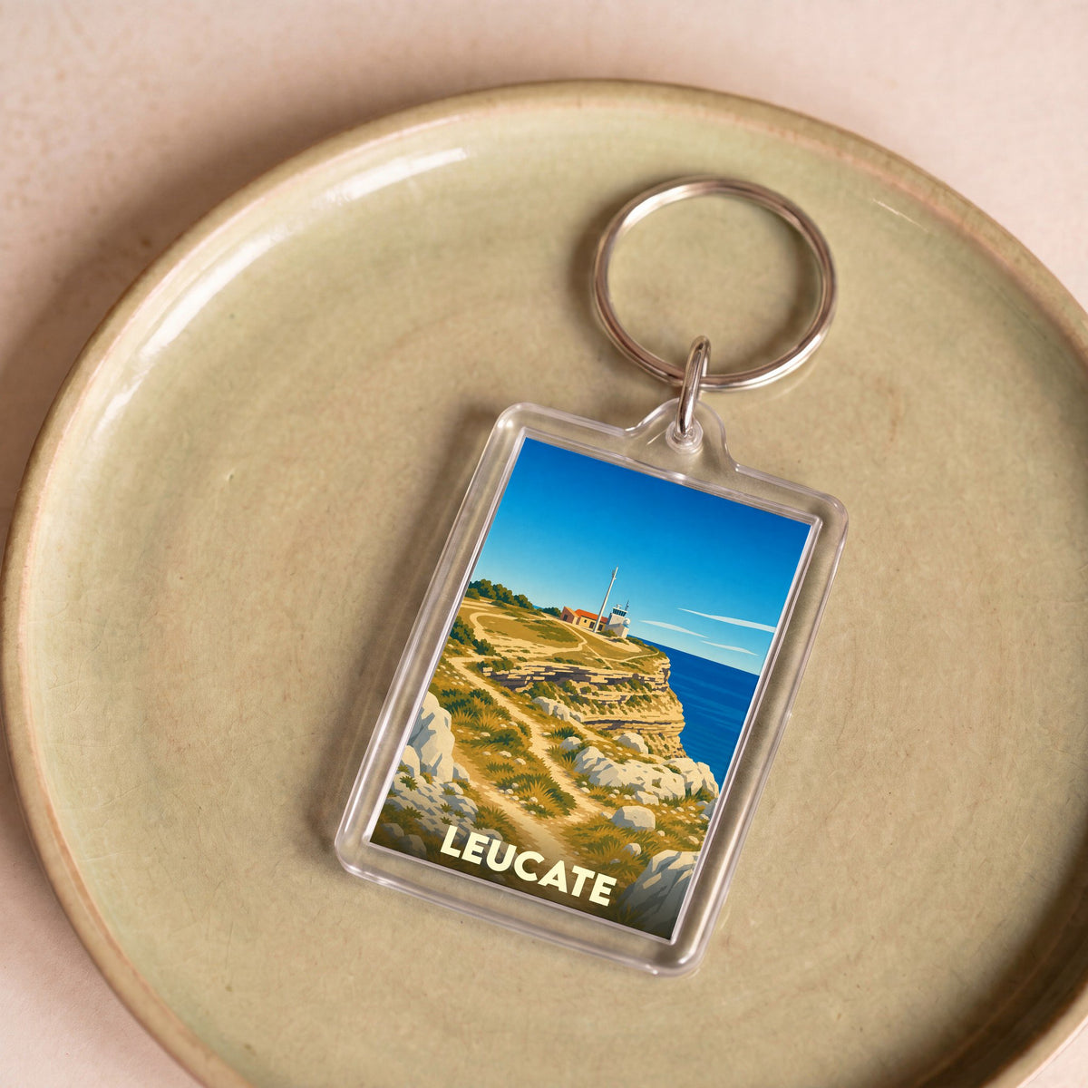 Porte-clés souvenir de la ville de Leucate avec une illustration stylisée de son phare et de ses falaises.