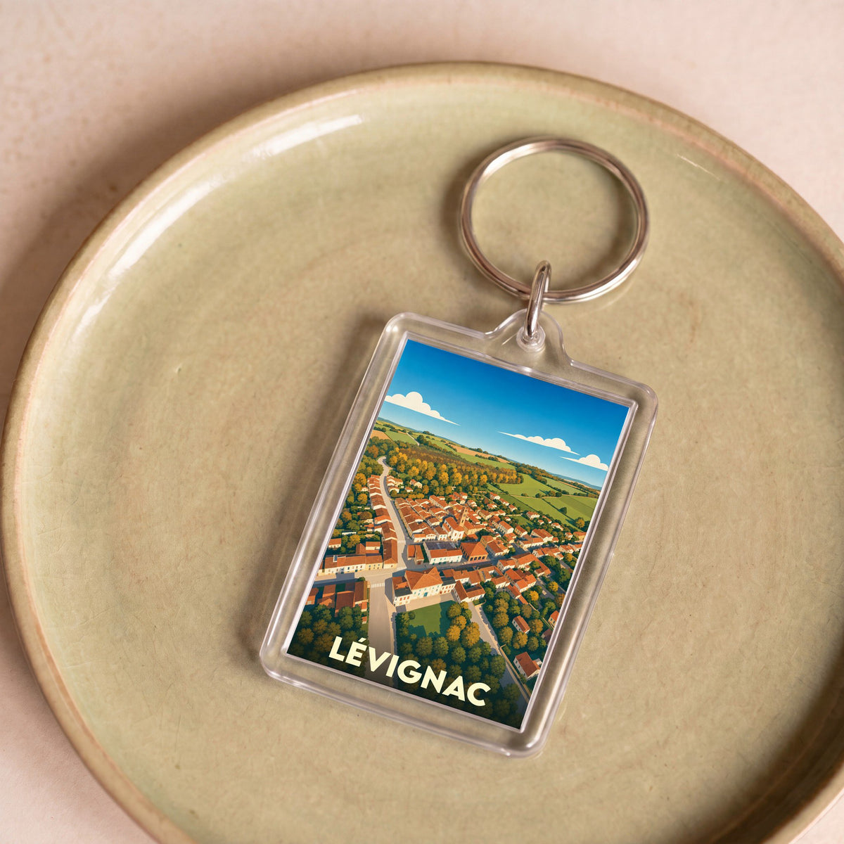 Porte-clés souvenir de la ville de Lévignac avec une illustration aérienne stylisée.