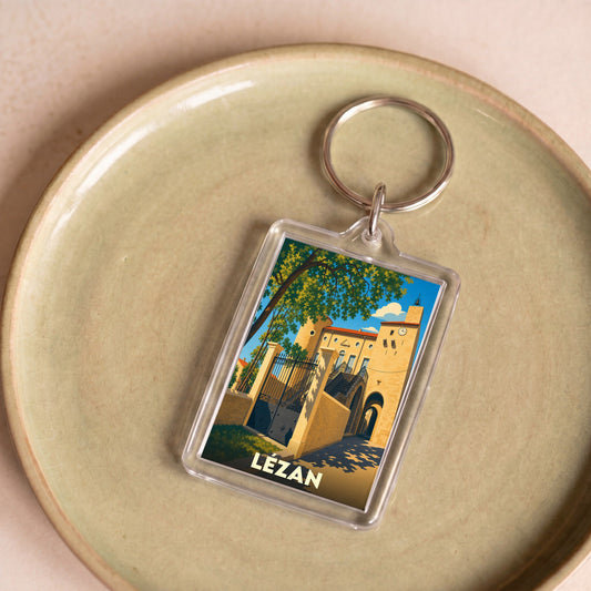 Porte-clés souvenir de la ville de Lézan avec une illustration stylisée de son patrimoine architectural.
