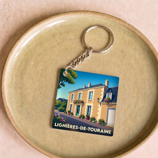 Porte-clés souvenir de la ville de Lignières-de-Touraine avec une illustration stylisée d'une maison fleurie.