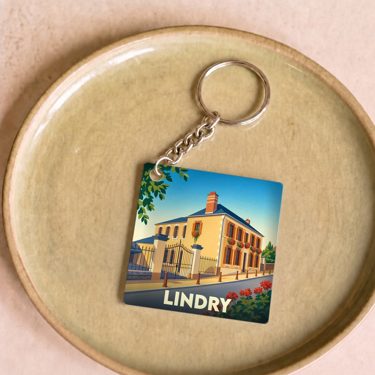 Porte-clés souvenir de la ville de Lindry avec une illustration stylisée d'une maison de bourg.