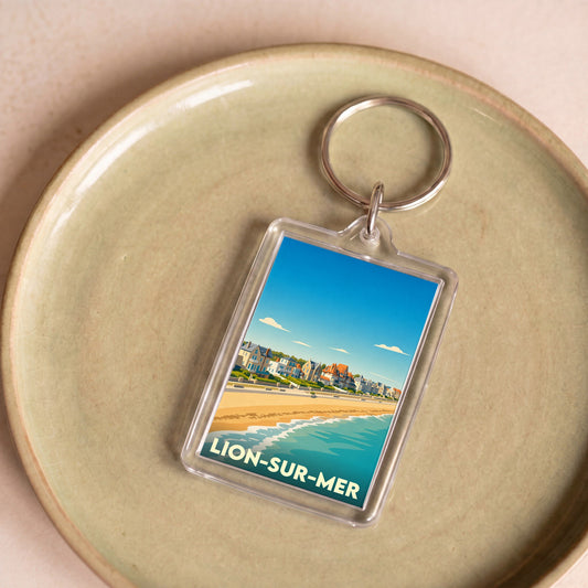 Porte-clés souvenir de la ville de Lion-sur-Mer avec une illustration stylisée de sa plage et de son front de mer.