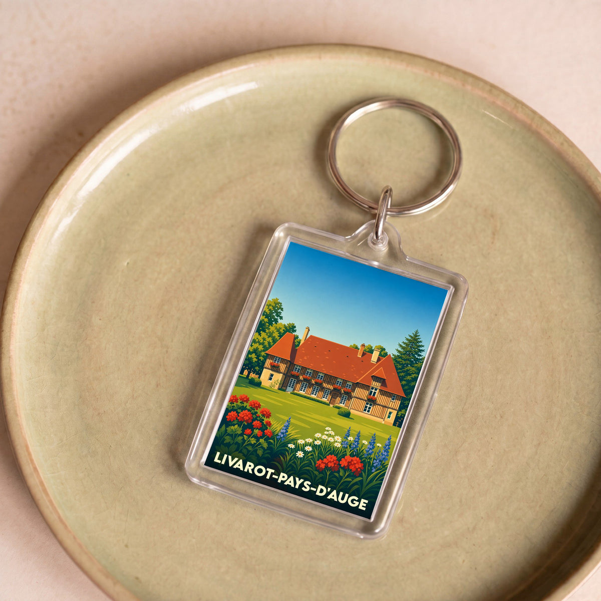 Porte-clés souvenir de la ville de Livarot-Pays-d'Auge avec une illustration stylisée d'un manoir normand.