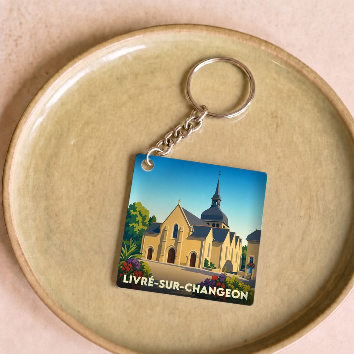 Porte-clés souvenir de la ville de Livré-sur-Changeon avec une illustration stylisée de son église.