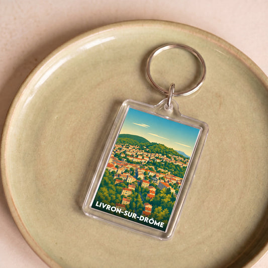 Porte-clés souvenir de la ville de Livron-sur-Drôme avec une illustration panoramique stylisée.