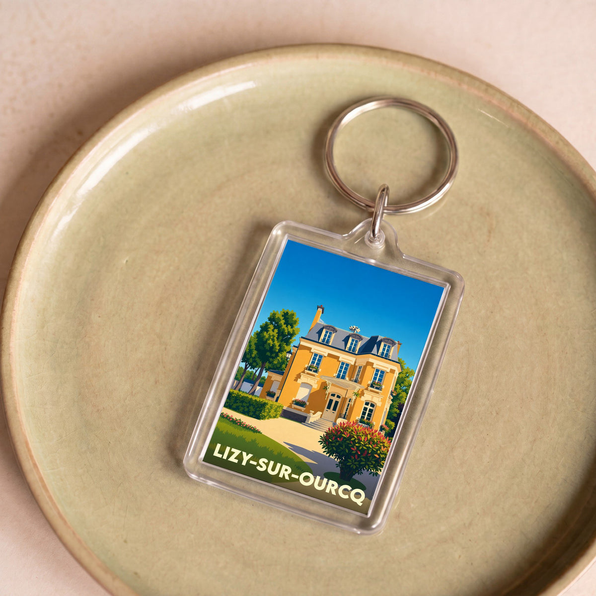 Porte-clés souvenir de la ville de Lizy-sur-Ourcq avec une illustration stylisée d'une demeure bourgeoise.