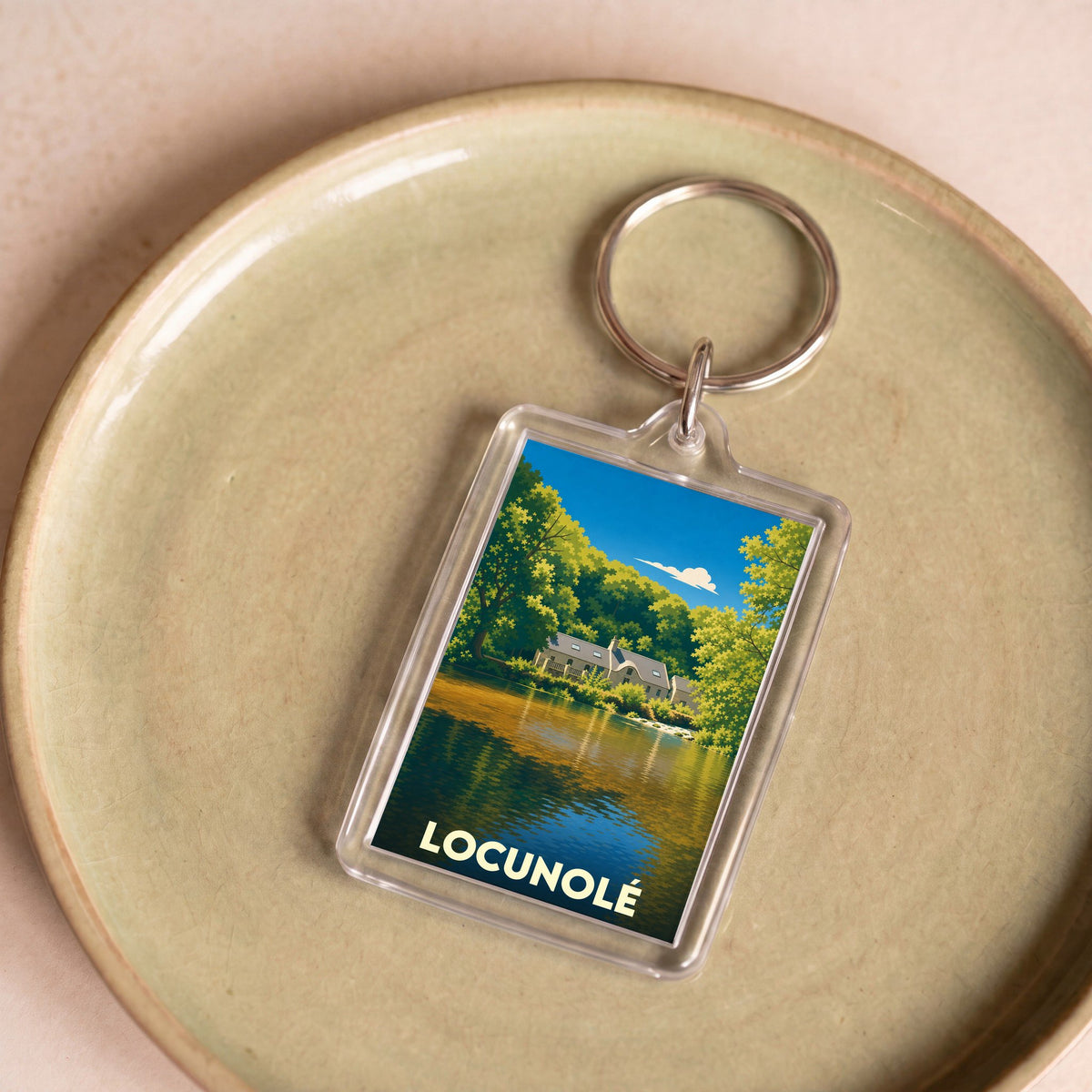 Porte-clés souvenir de la ville de Locunolé avec une illustration stylisée d'un paysage de bord de l'eau.