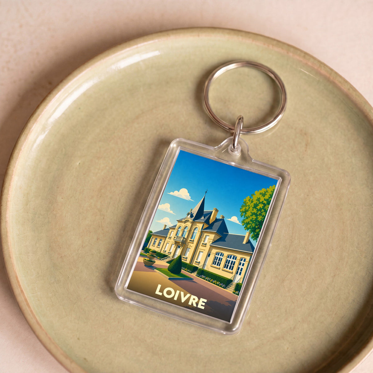 Porte-clés souvenir de la ville de Loivre avec une illustration stylisée d'une grande demeure.