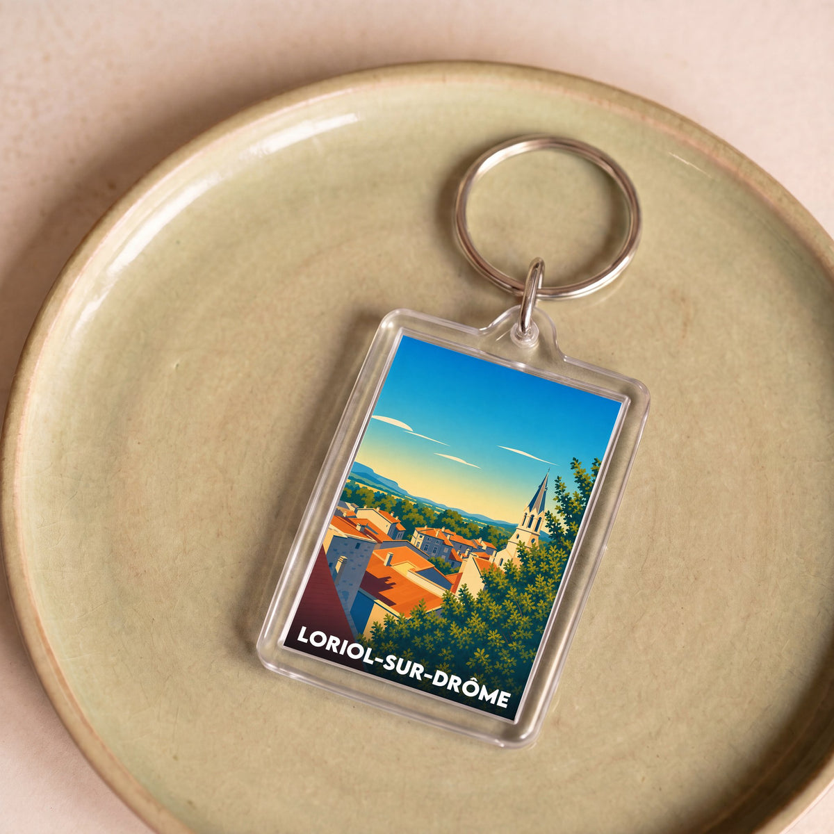Porte-clés souvenir de la ville de Loriol-sur-Drôme avec une illustration stylisée d'un paysage urbain.