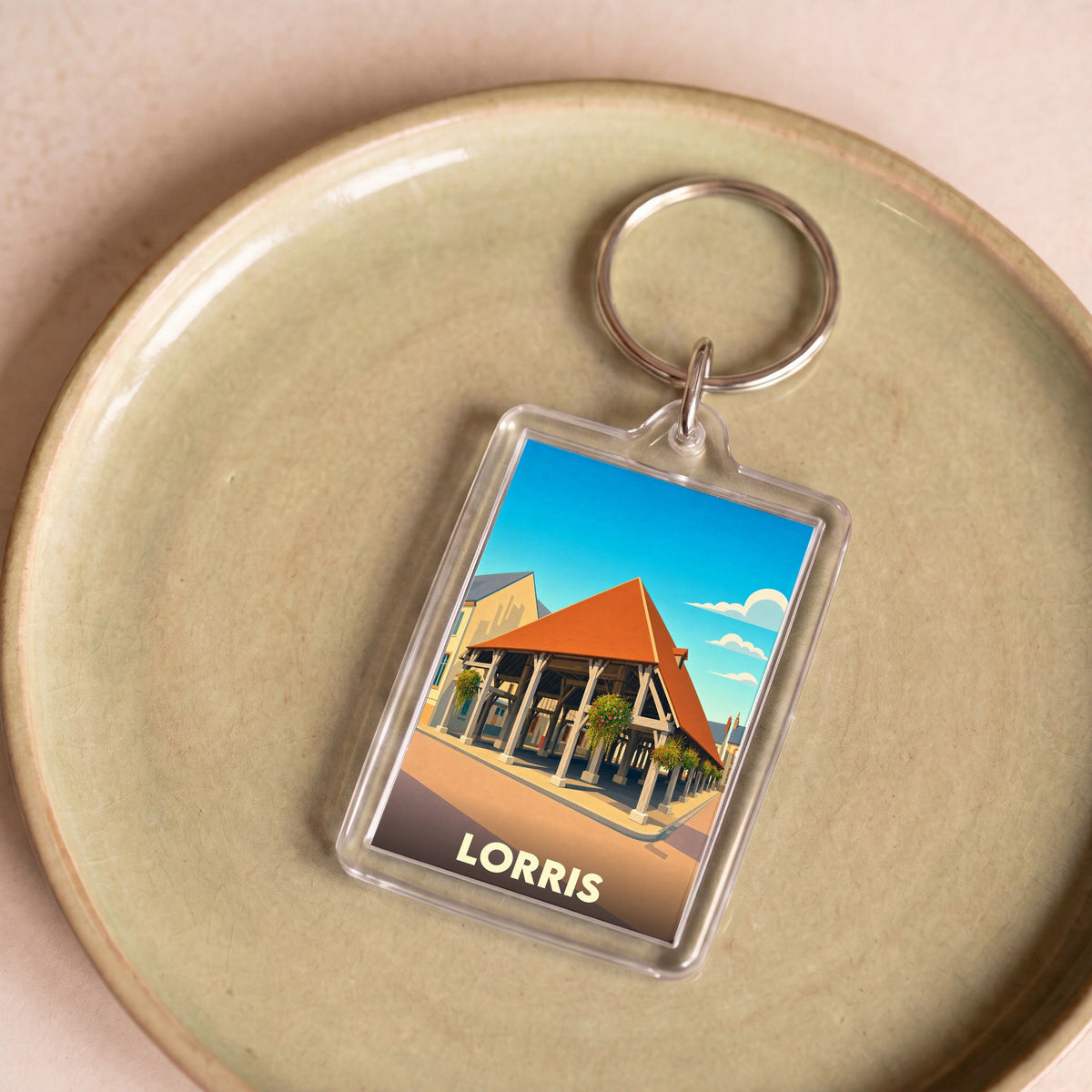 Porte-clés souvenir de la ville de Lorris avec une illustration stylisée de ses halles historiques.