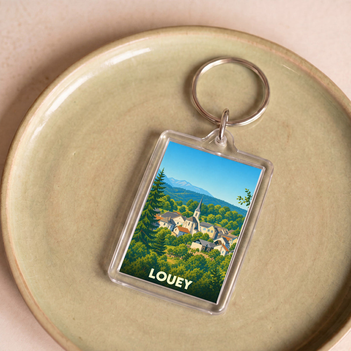 Porte-clés souvenir de la ville de Louey avec une illustration stylisée d'un village de montagne.