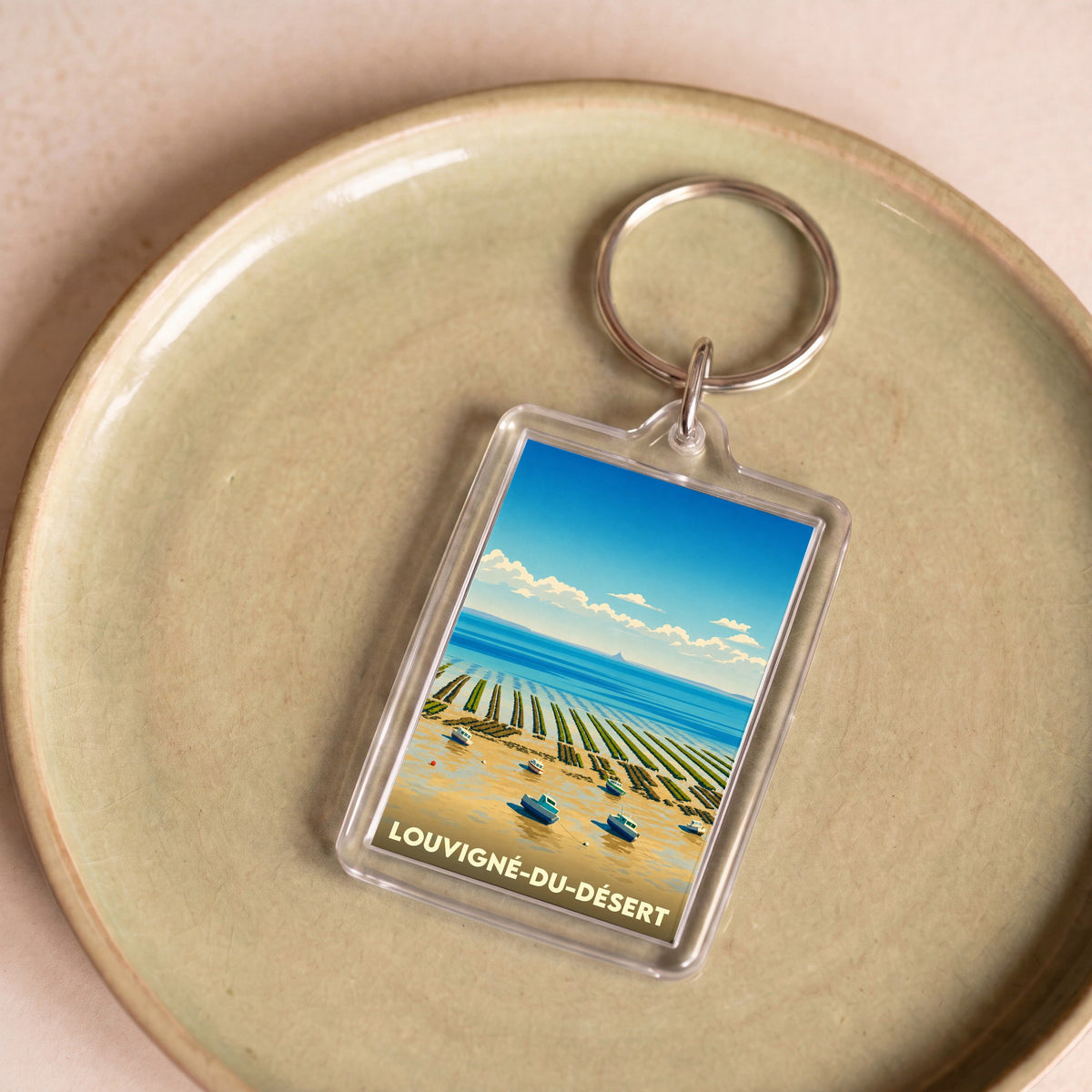 Porte-clés souvenir de Louvigné-du-Désert illustré d'un paysage côtier stylisé.