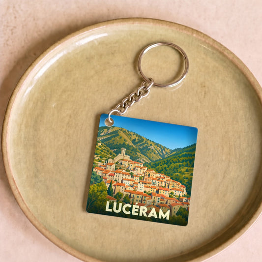 Porte-clés souvenir de la ville de Lucéram avec une illustration stylisée d'un village perché en montagne.