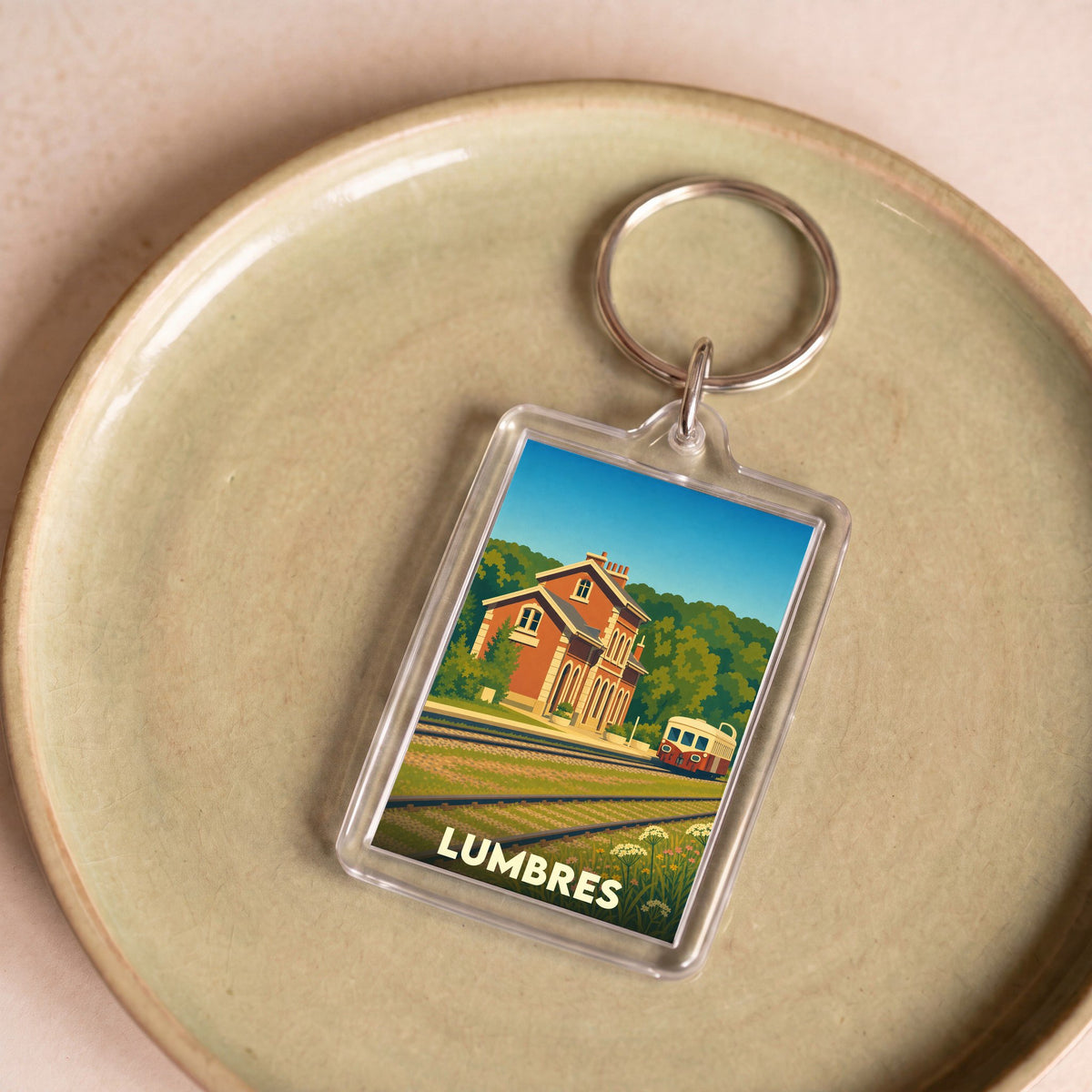 Porte-clés souvenir de la ville de Lumbres avec une illustration stylisée de sa gare et d'un autorail.