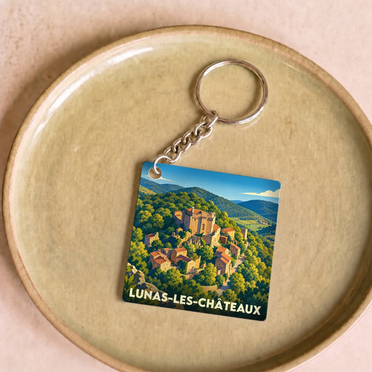 Porte-clés souvenir de la ville de Lunas-les-Châteaux avec une illustration stylisée de son paysage et de ses châteaux.