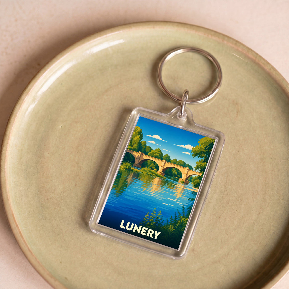 Porte-clés souvenir de la ville de Lunery avec une illustration stylisée d'un pont enjambant une rivière.