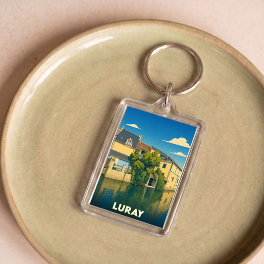 Porte-clés souvenir de la ville de Luray avec une illustration stylisée d'une maison au bord de l'eau.