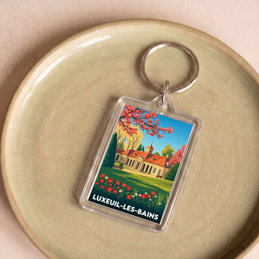 Porte-clés souvenir de la ville de Luxeuil-les-Bains avec une illustration stylisée.