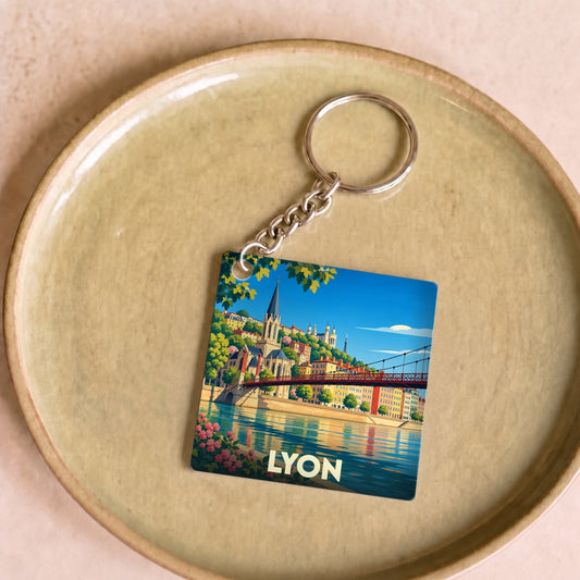 Porte-clés souvenir de la ville de Lyon avec une illustration stylisée des quais de Saône et de l'église Saint-Georges.