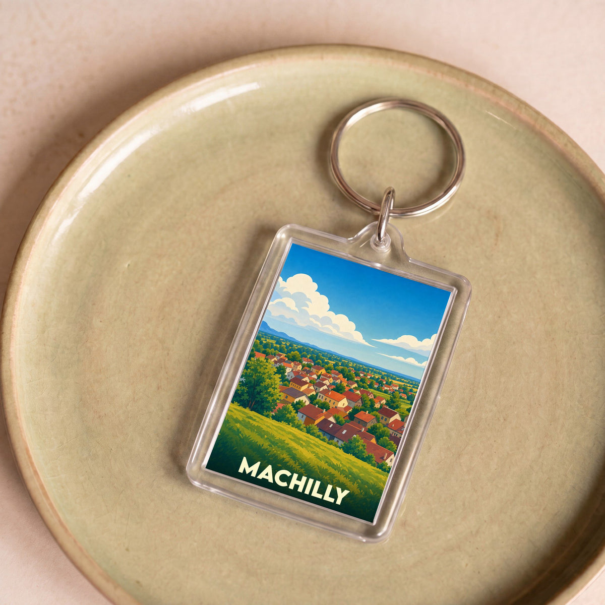 Porte-clés souvenir de la ville de Machilly avec une illustration stylisée de son paysage urbain et champêtre.