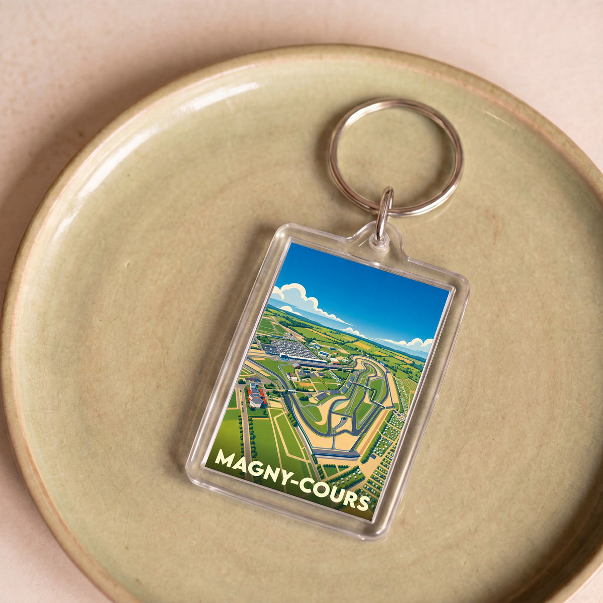 Porte-clés souvenir de la ville de Magny-Cours avec une illustration stylisée du circuit automobile.
