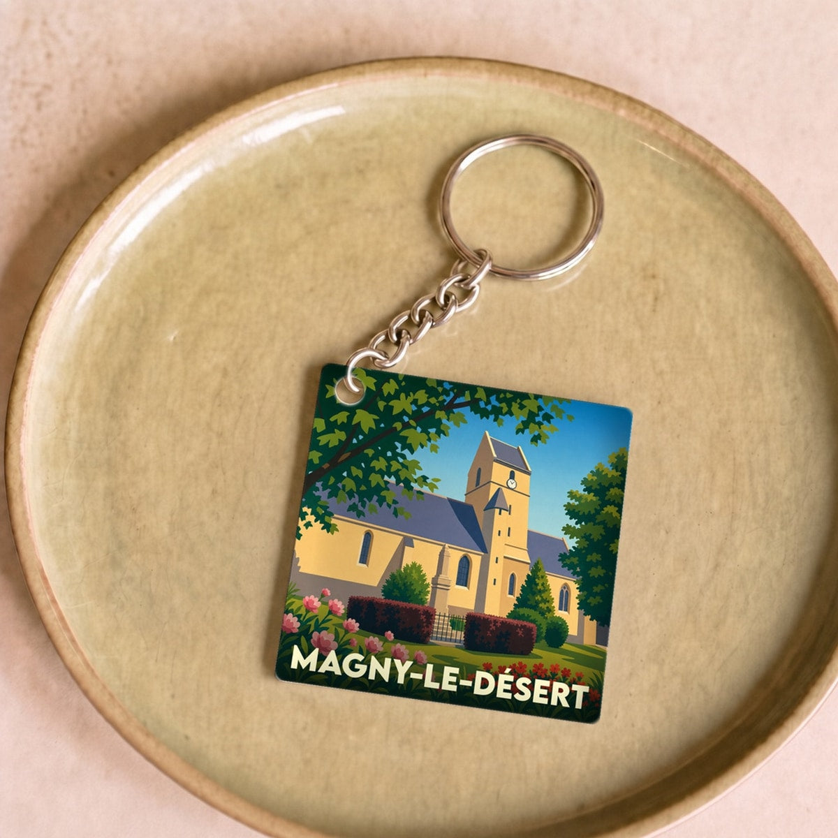 Porte-clés souvenir de la ville de Magny-le-Désert avec une illustration stylisée de son église.