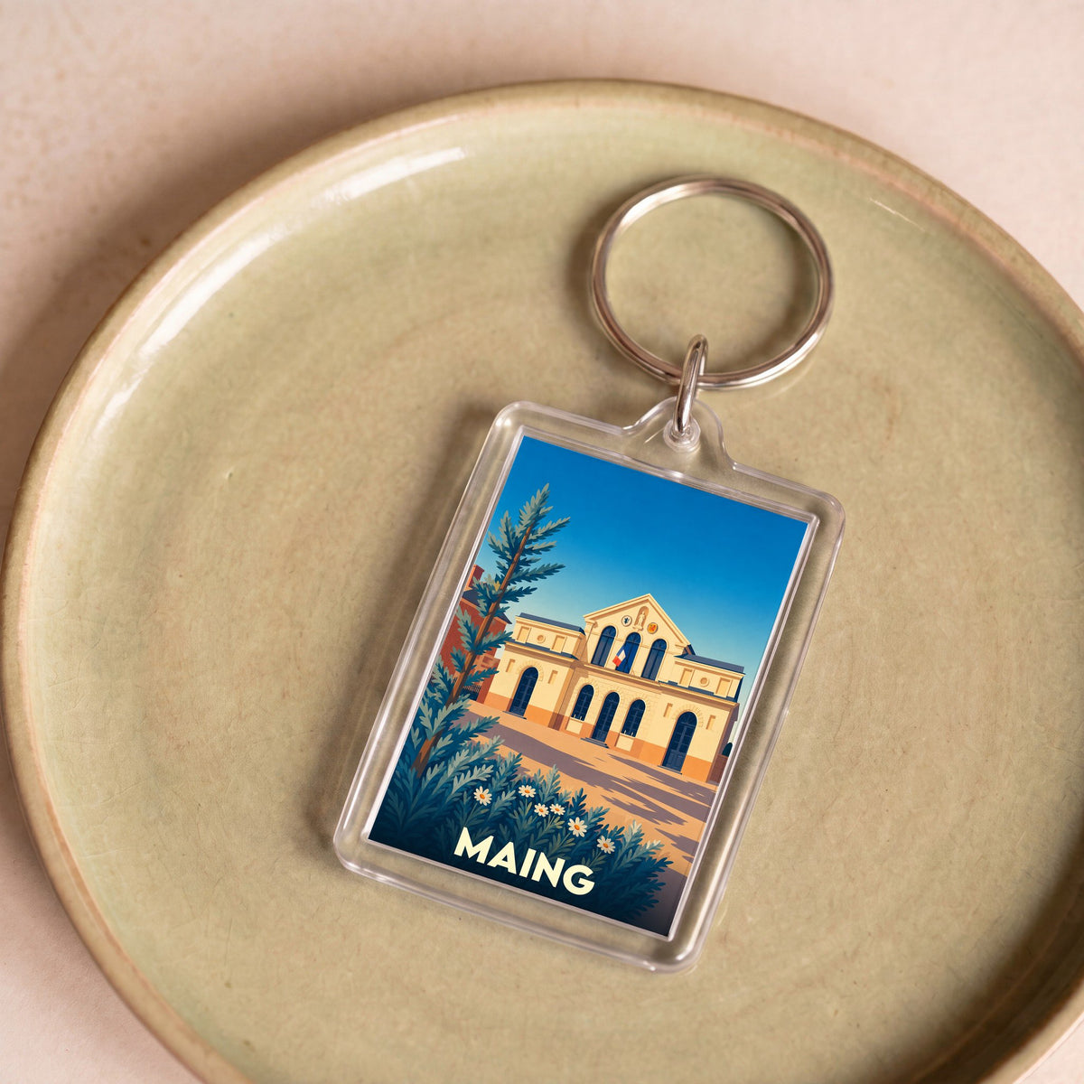 Porte-clés souvenir de la ville de Maing avec une illustration stylisée de sa mairie.