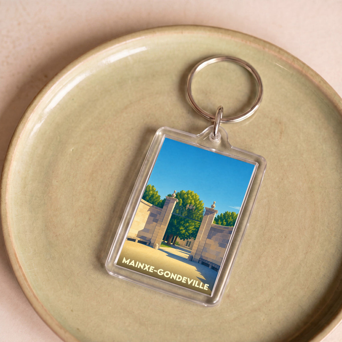 Porte-clés souvenir de la ville de Mainxe-Gondeville avec une illustration stylisée d'un portail monumental.