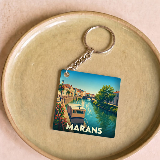 Porte-clés souvenir de la ville de Marans avec une illustration stylisée d'un canal et de bateaux.