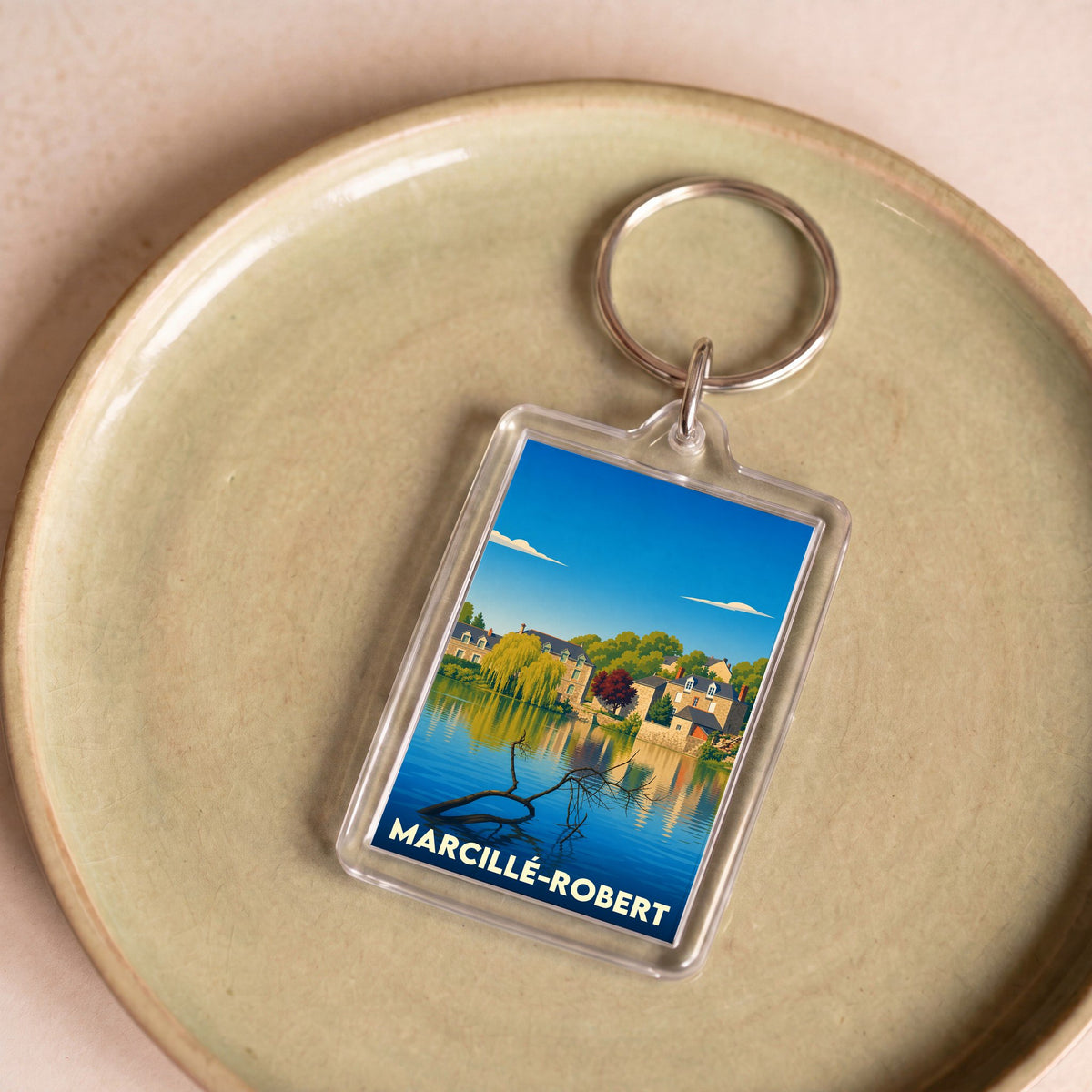 Porte-clés souvenir de la ville de Marcillé-Robert avec une illustration stylisée d'un paysage au bord de l'eau.