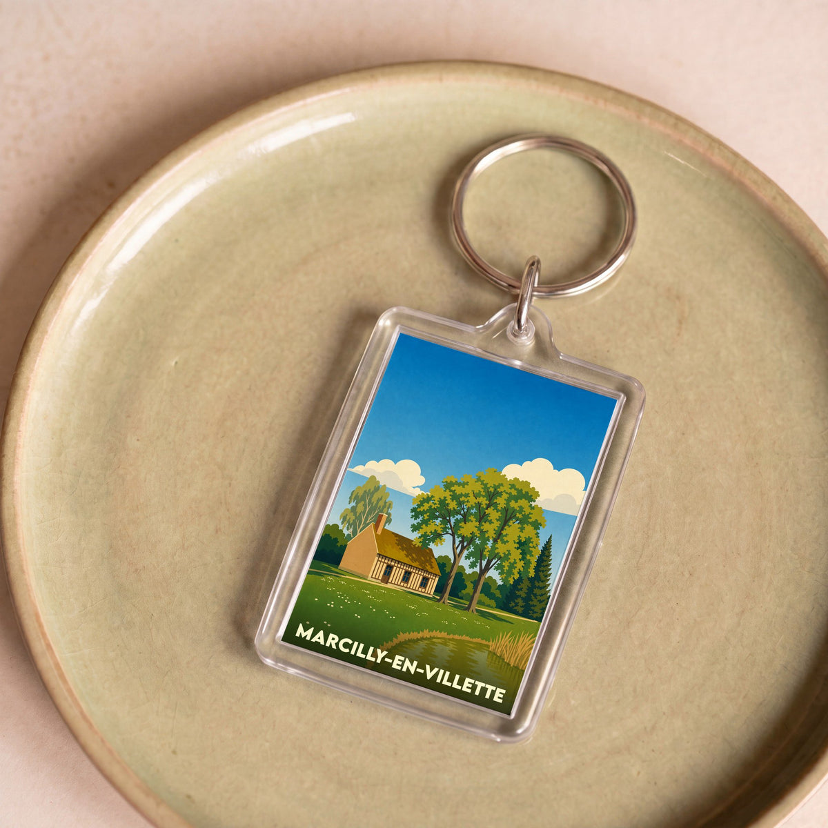Porte-clés souvenir de la ville de Marcilly-en-Villette avec une illustration champêtre stylisée.