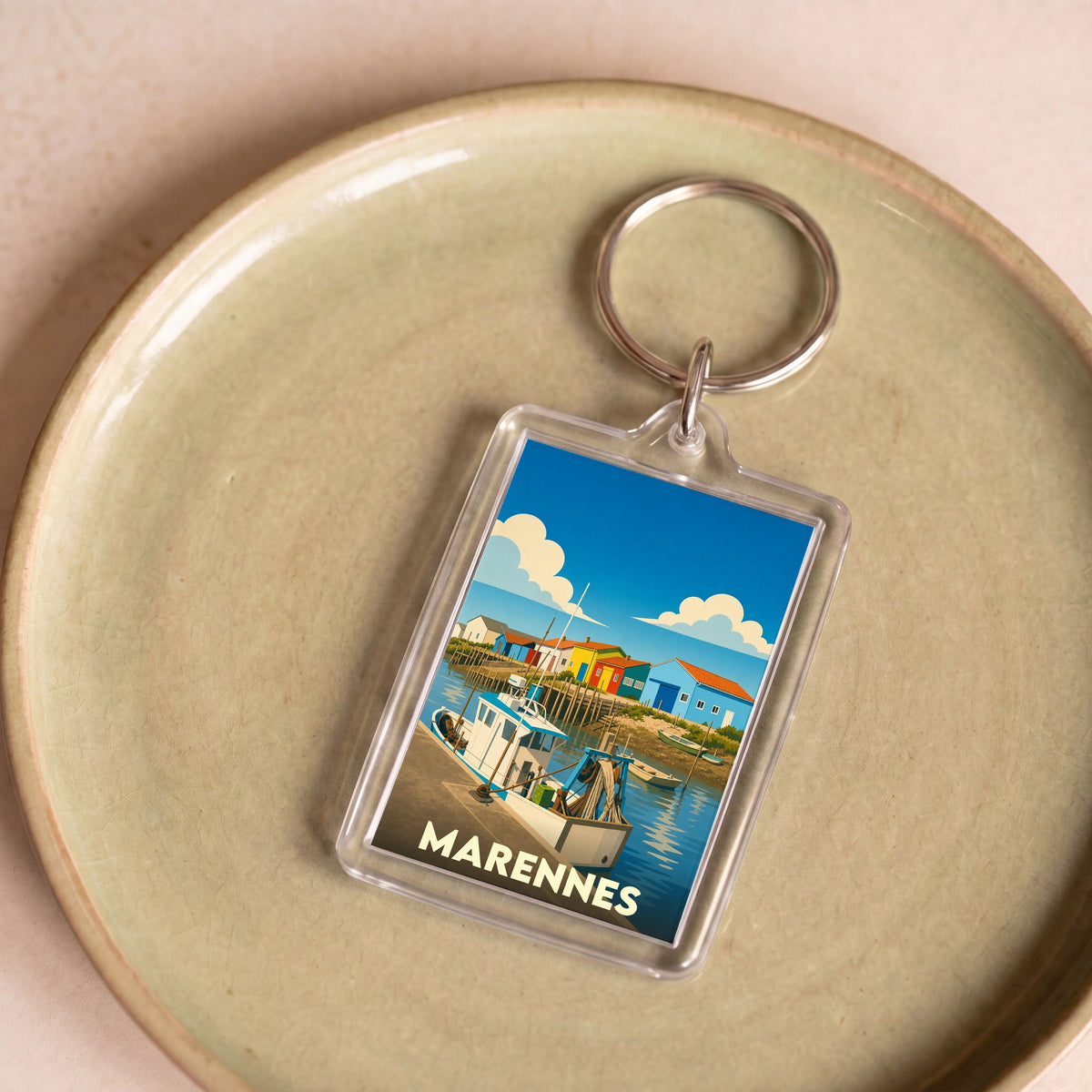 Porte-clés souvenir de la ville de Marennes avec une illustration stylisée d'un port de pêche.