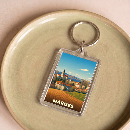 Porte-clés souvenir de la ville de Margès avec une illustration stylisée de son paysage et de son église.