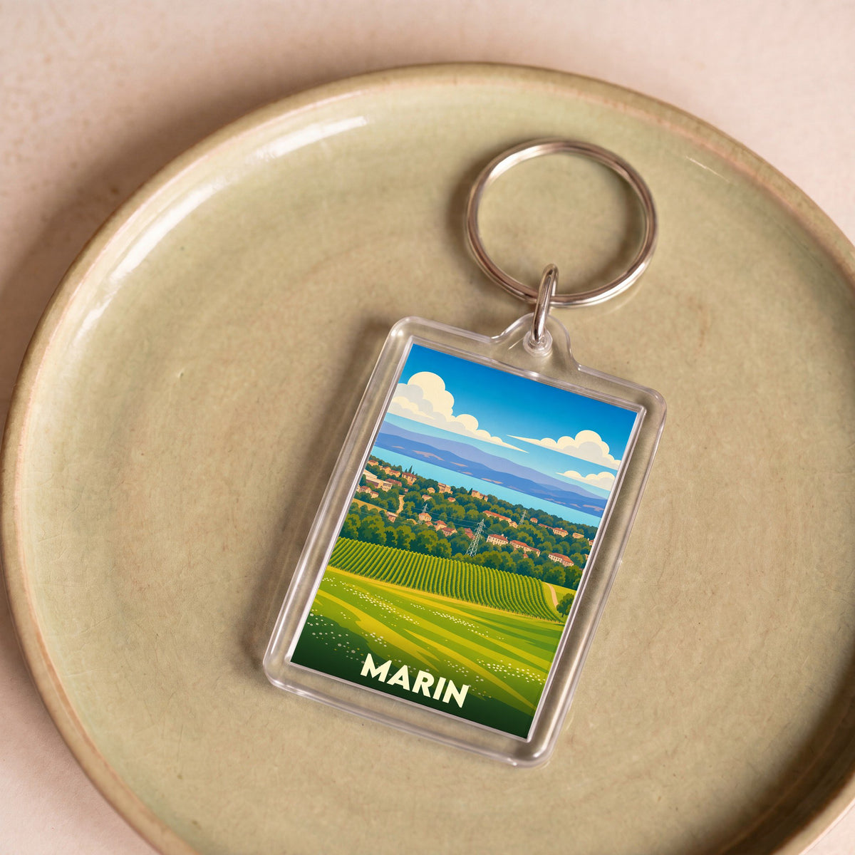 Porte-clés souvenir de la ville de Marin avec une illustration stylisée de paysages vallonnés.