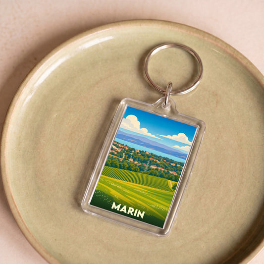 Porte-clés souvenir de la ville de Marin avec une illustration stylisée de paysages vallonnés.