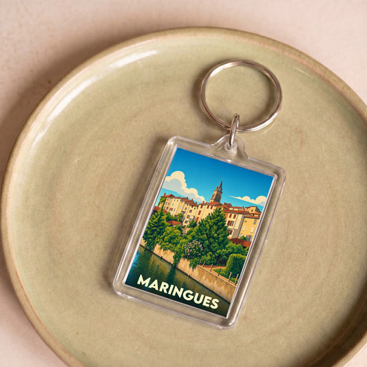 Porte-clés souvenir de la ville de Maringues avec une illustration stylisée d'un paysage urbain au bord de l'eau.