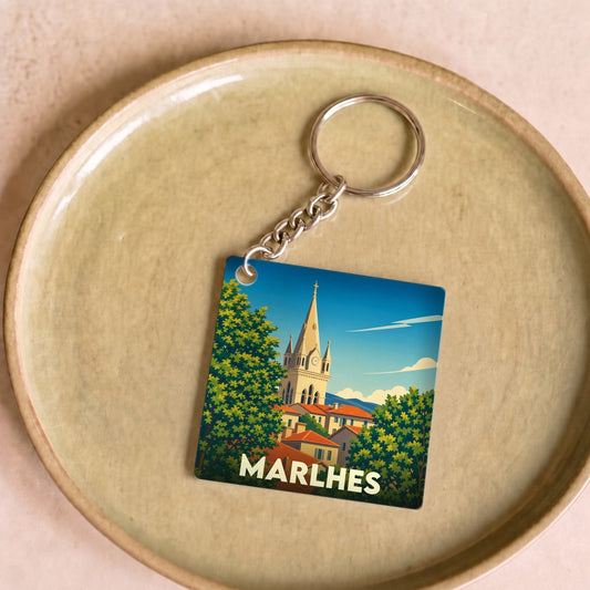 Porte-clés souvenir de la ville de Marlhes avec une illustration stylisée d'un clocher et de toits orangés.