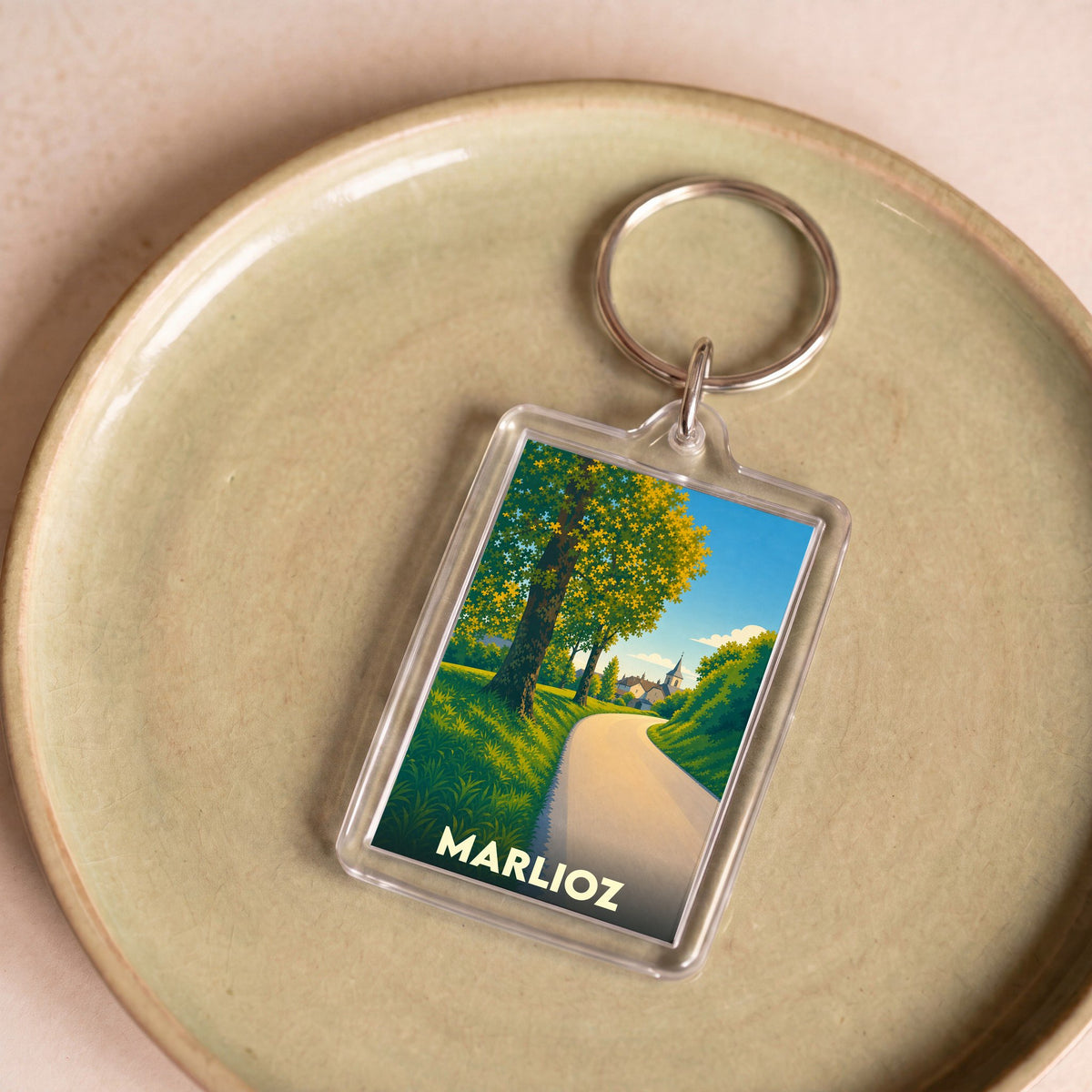 Porte-clés souvenir de la ville de Marlioz avec une illustration stylisée de paysage.