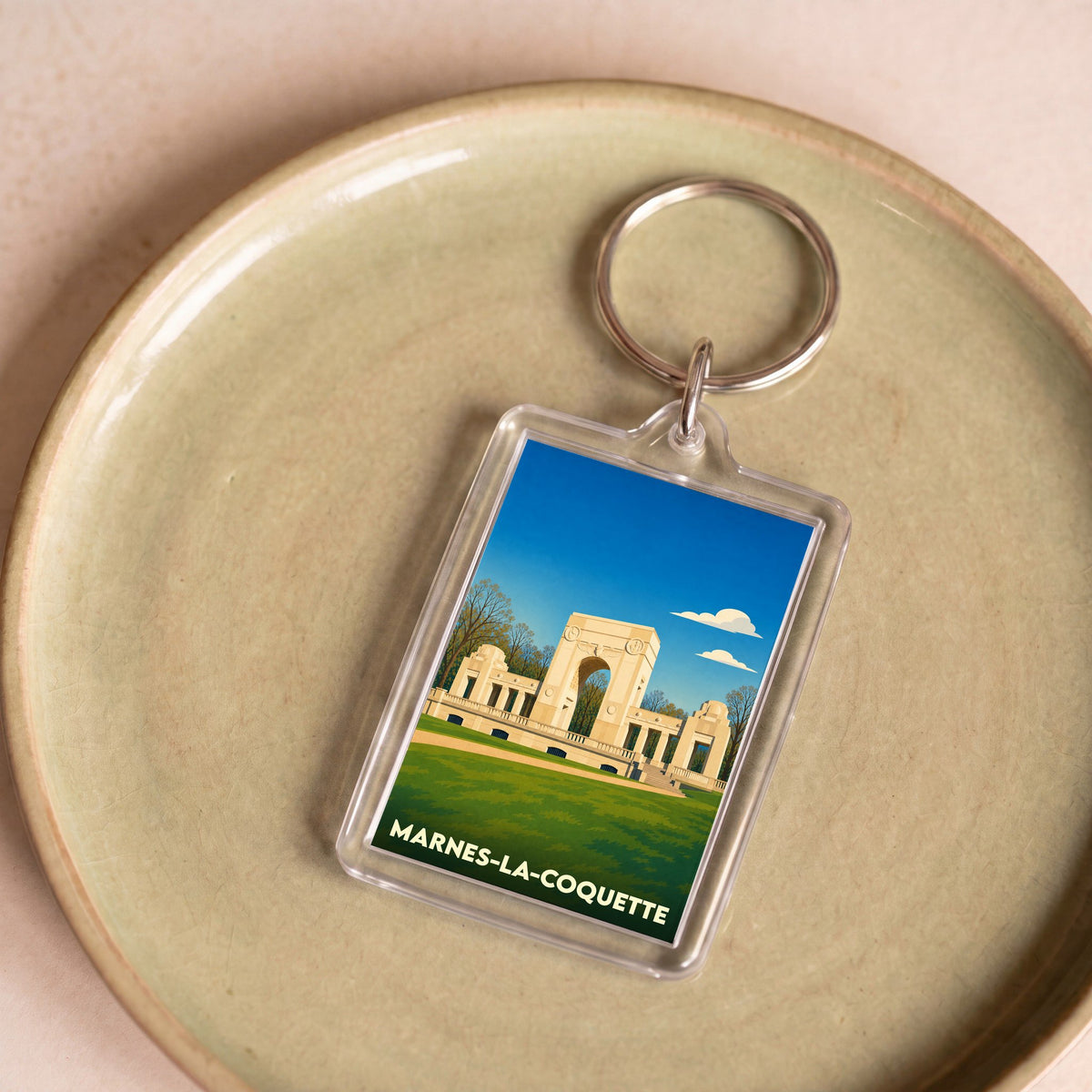 Porte-clés souvenir de la ville de Marnes-la-Coquette avec une illustration stylisée de son mémorial.