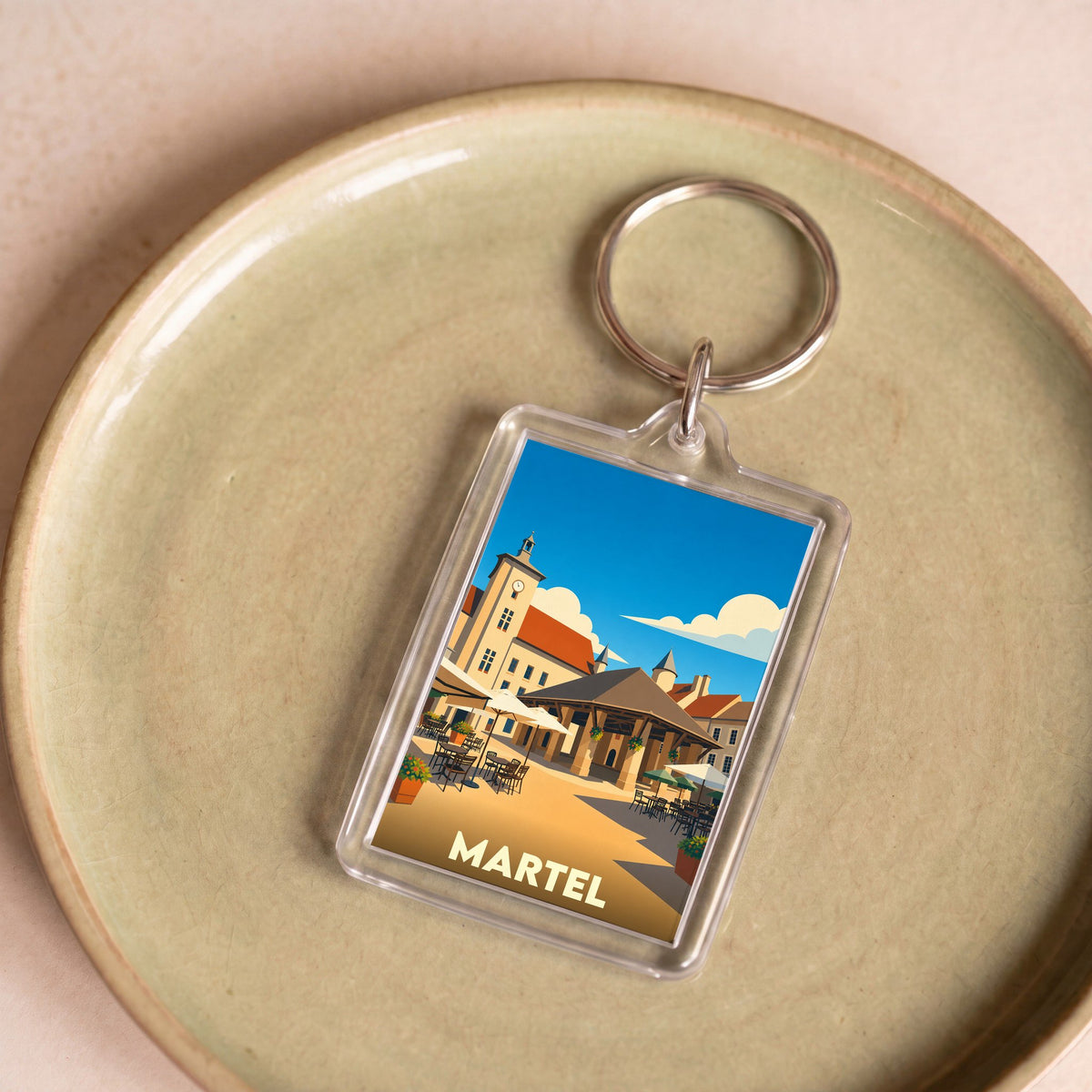 Porte-clés souvenir de la ville de Martel avec une illustration stylisée de sa place principale.