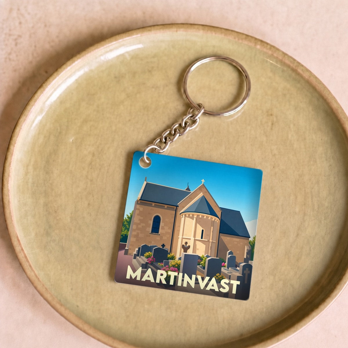 Porte-clés souvenir de la ville de Martinvast avec une illustration stylisée de son église et de son cimetière.