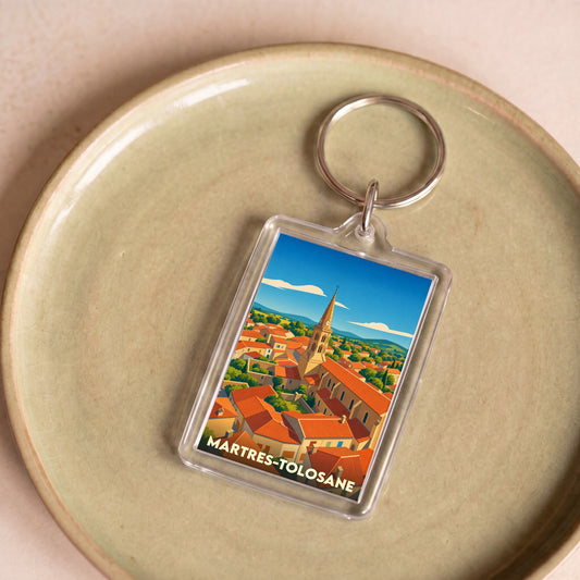 Porte-clés souvenir de la ville de Martres-Tolosane avec une illustration stylisée de ses toits et de son clocher.