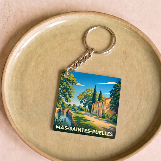 Porte-clés souvenir de la ville de Mas-Saintes-Puelles avec une illustration stylisée d'un paysage de canal.