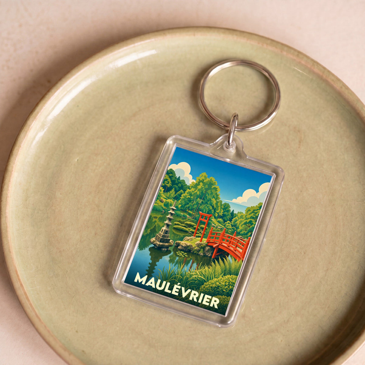 Porte-clés souvenir de la ville de Maulévrier illustrant son jardin japonais avec un pont rouge et une pagode.
