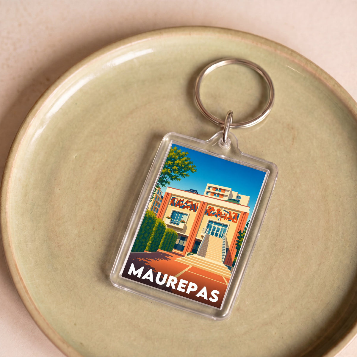 Porte-clés souvenir de la ville de Maurepas avec une illustration stylisée.