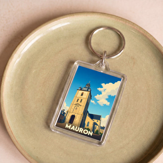 Porte-clés souvenir de la ville de Mauron avec une illustration stylisée de son église sous un ciel bleu.